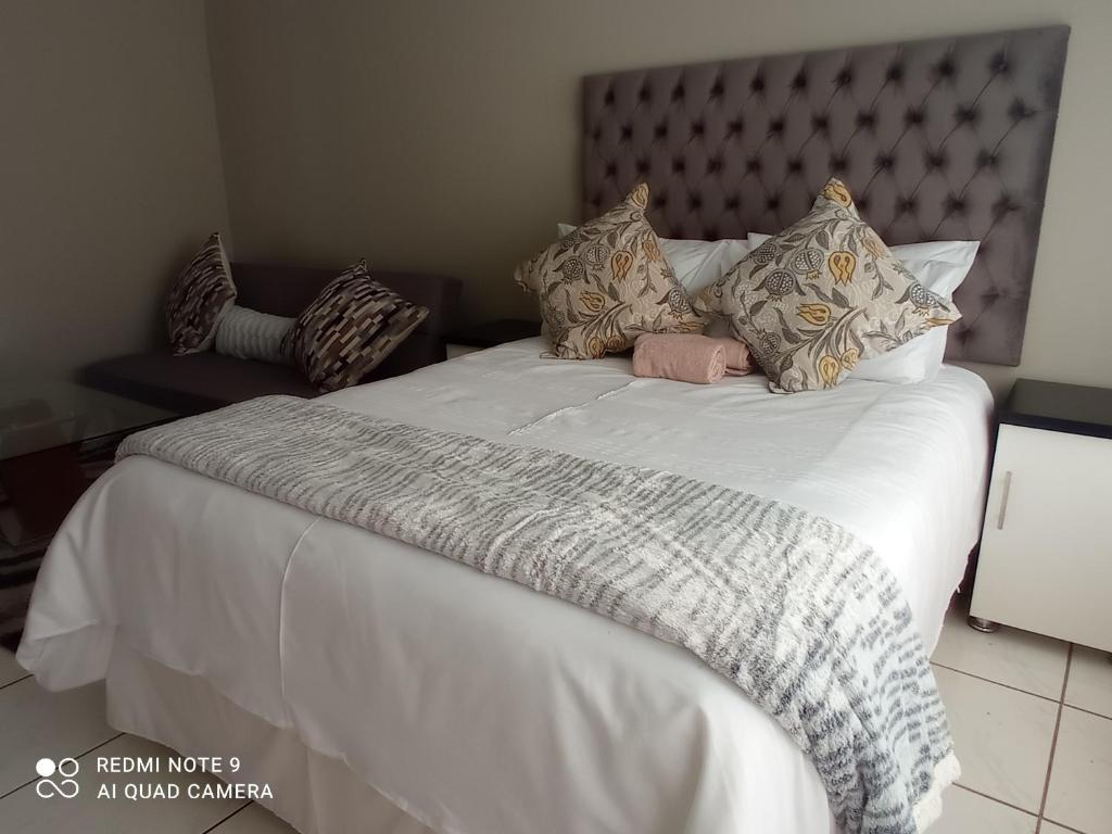 a large bed with white sheets and pillows at Atholl Heights Home in Westville