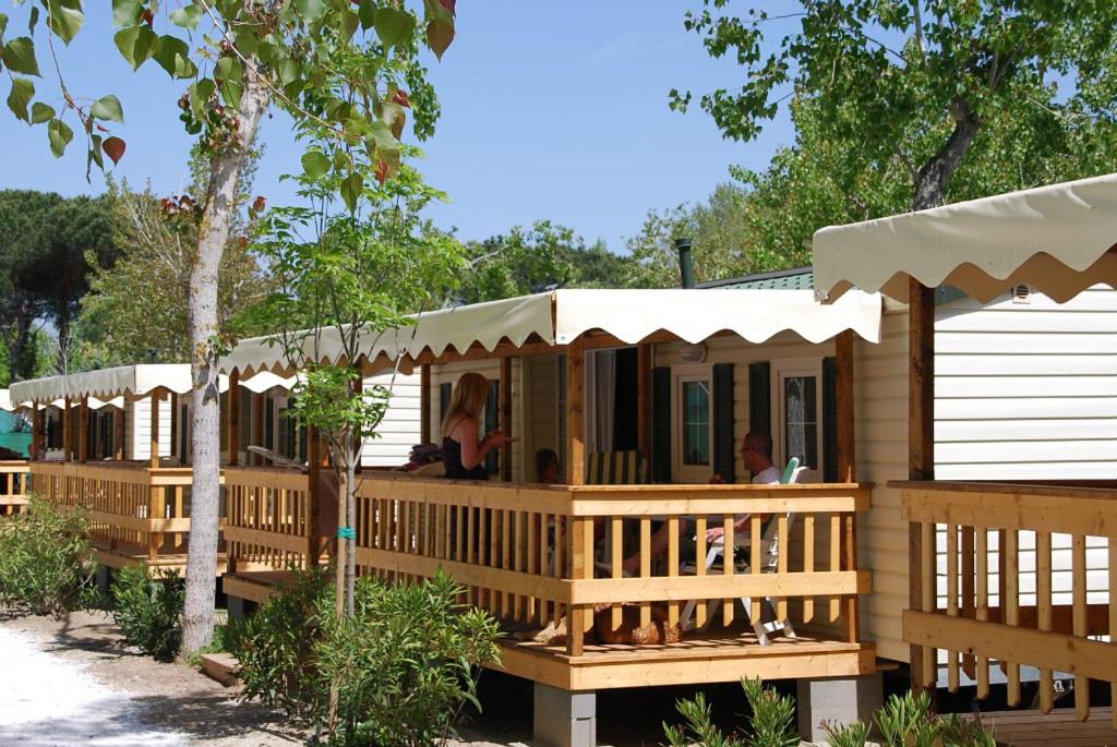 duży drewniany dom z gankiem z ludźmi siedzącymi na nim w obiekcie Chalet 4 or 6 persons Toscana Viareggio Camping Bosco Verde Italië w mieście Torre del Lago Puccini