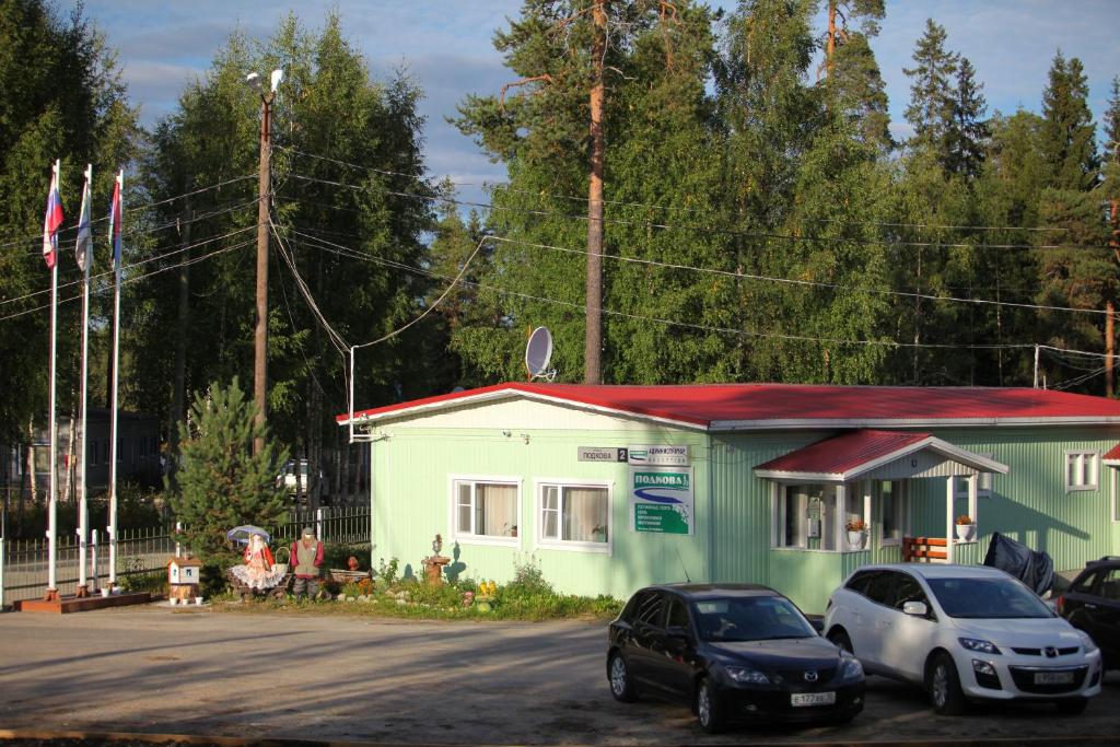 a green building with cars parked in front of it at Podkova in Kostomuksha