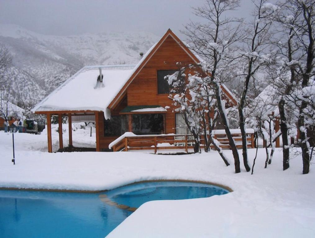 a log cabin in the snow with a swimming pool at Cabañas Los Nevados in Nevados de Chillan