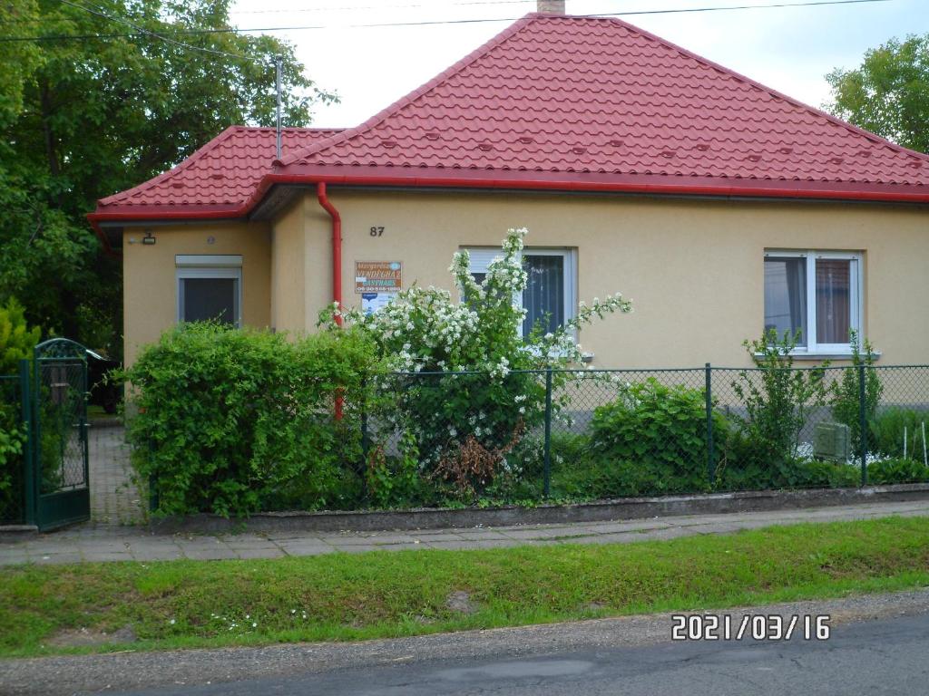 een huis met een rood dak en een hek bij Margaréta Vendégház in Fehérvárcsurgó
