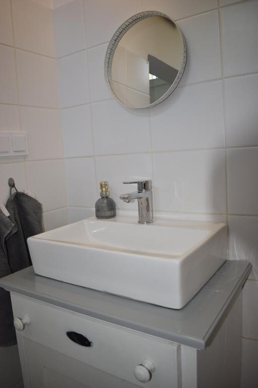 biała umywalka z lustrem na blacie w obiekcie Malomszeg Apartman 2 w mieście Pecz