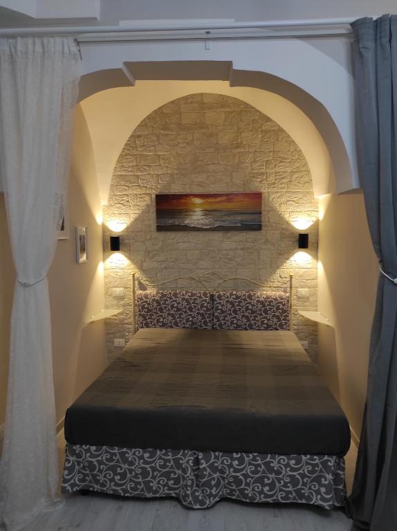 uma cama num quarto com uma parede de pedra em Apartment Casa Felice em Ostuni