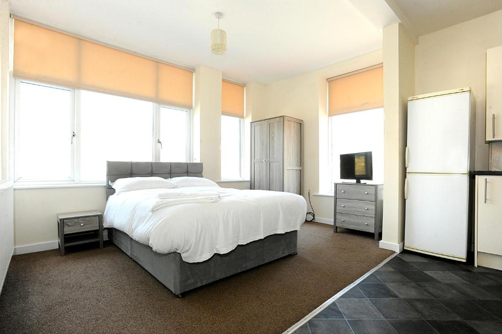 a bedroom with a large bed with white sheets and windows at APARTMENT in CENTRAL HALIFAX in Halifax