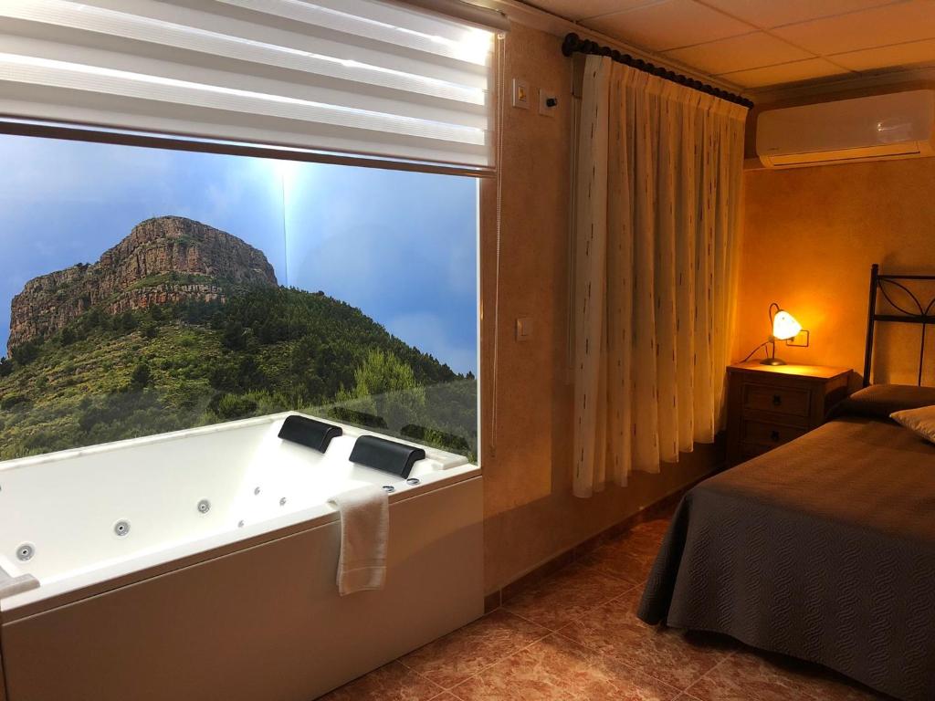 Cases Rurals El Castell في Torres-Torres: غرفة مع نافذة كبيرة مع حوض استحمام وجبل