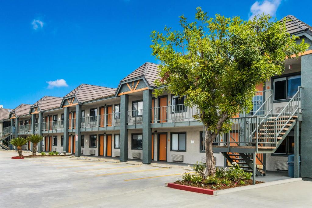 a row of apartment buildings with a tree in a parking lot at Hotel Hacienda at Ontario Ranch in Ontario