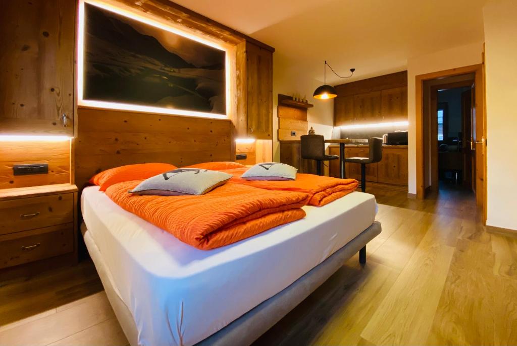 um quarto com uma cama grande e um cobertor laranja em Chalet Nicolin em Livigno