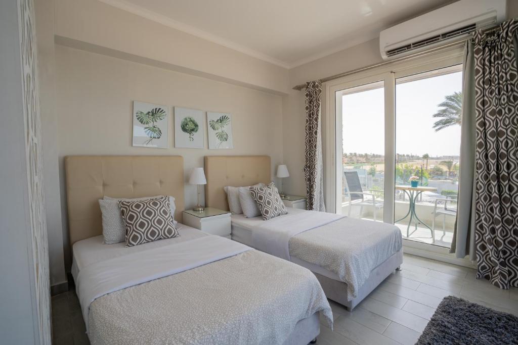 a bedroom with two beds and a large window at Sea Gull Marina Hotel in El Alamein