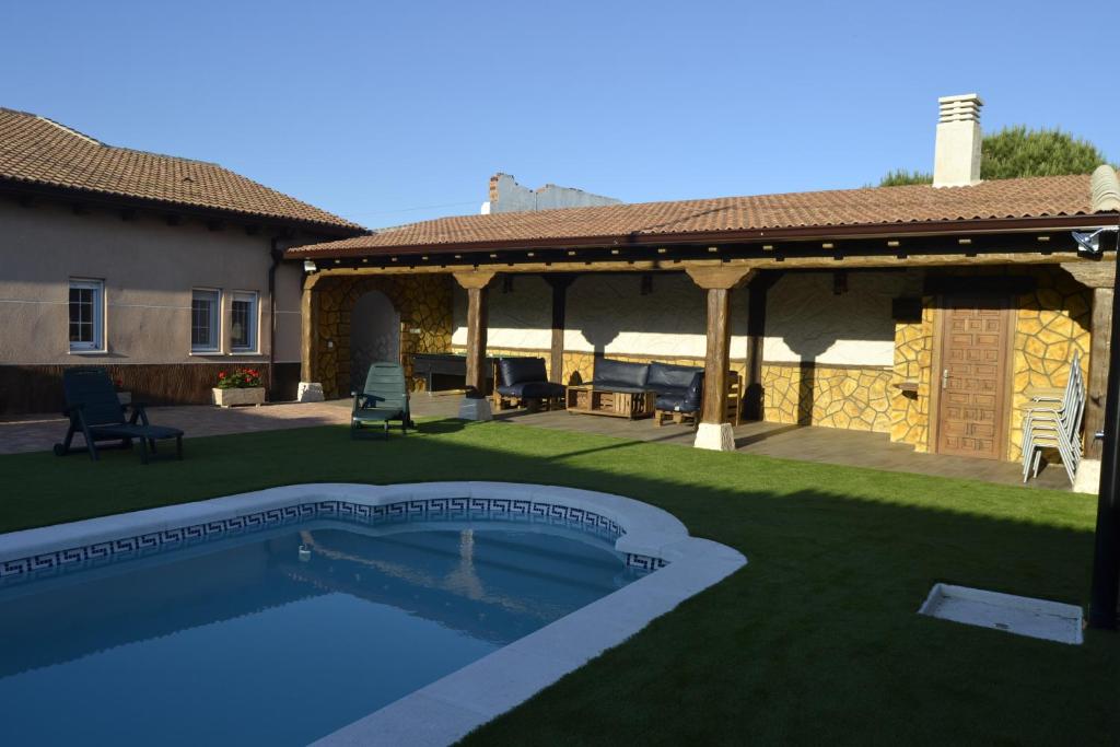 a backyard with a swimming pool and a house at El Capricho de los Carrascos in Juarros de Voltoya