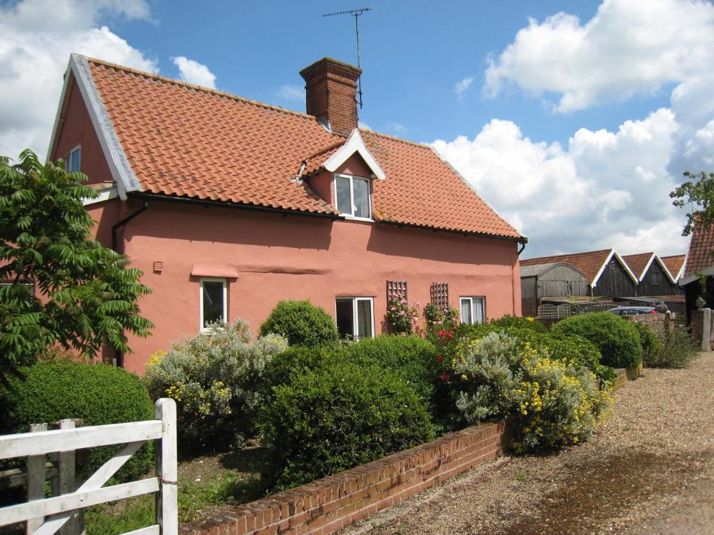 a pink house with a red roof at Colston Hall Cottages in Framlingham