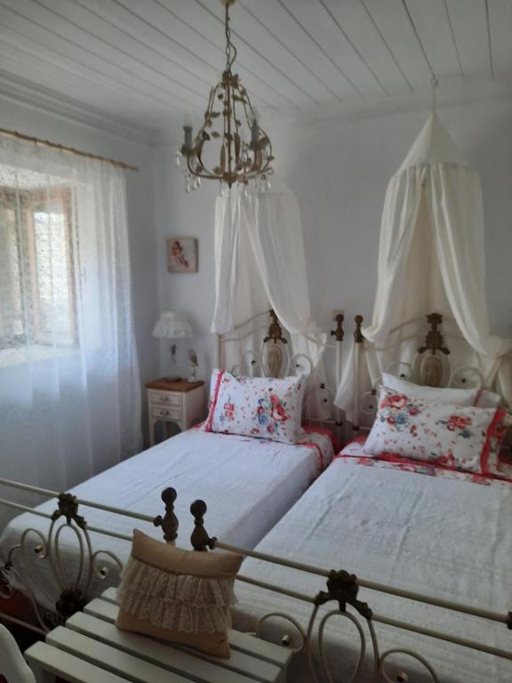 una camera con due letti e un lampadario a braccio di Casa di Sofiana by wood and stone ad Ágios Pétros