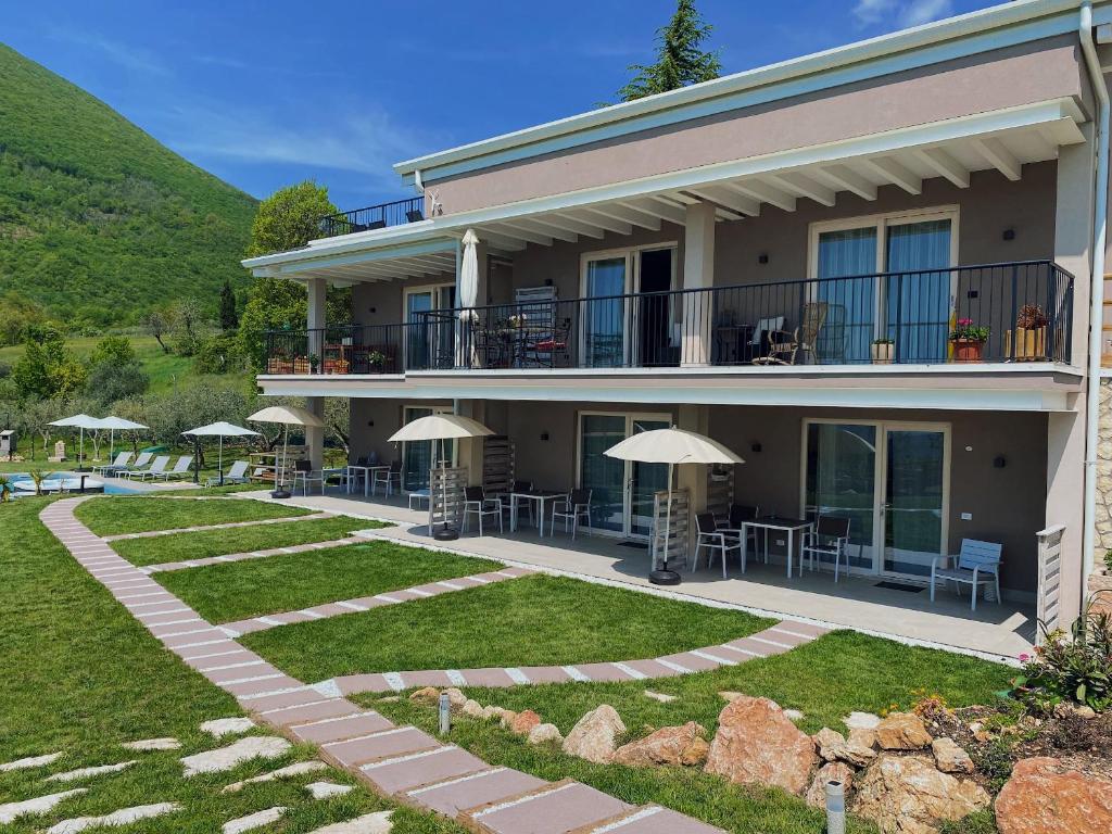 budynek ze stołami i parasolami na dziedzińcu w obiekcie Villa Nina - Apartments & Relax w mieście Caprino Veronese