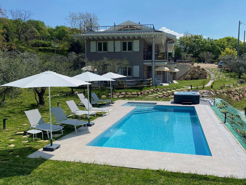 basen z leżakami i parasolami obok domu w obiekcie Villa Nina - Apartments & Relax w mieście Caprino Veronese