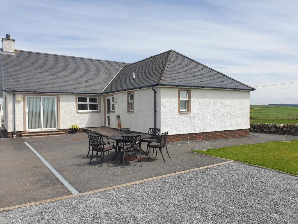 a table and chairs in front of a house at Challochmun Bungalow in Newton Stewart