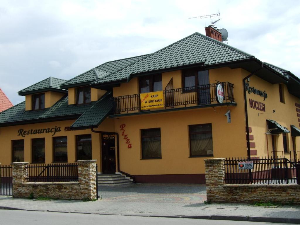 a large yellow building with a black roof at Hotel Primagor in Szydłowiec