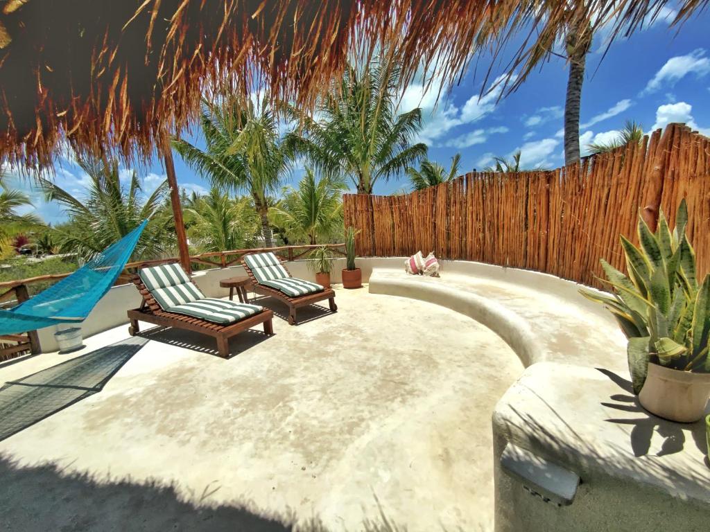 a patio with two chairs and a fence at Casa Cacahuate Holbox-Casa entera con jardin-Whole house with garden in Holbox Island