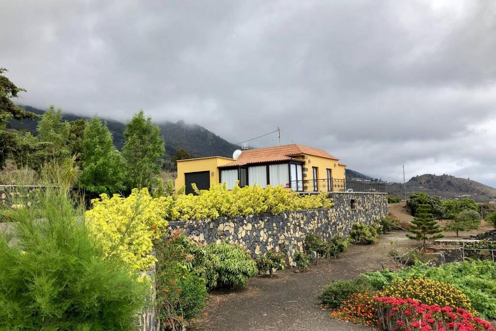 ein Haus mit einer Steinmauer im Garten in der Unterkunft CASA CUEVA DE LAS PALOMAS 1 in Las Manchas