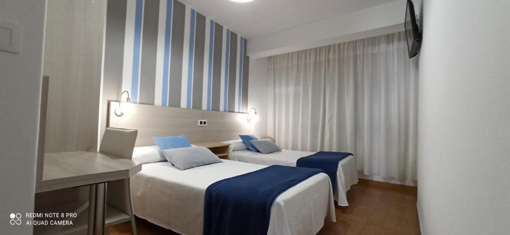フィニステレにあるHostal Rivasのベッド2台と鏡が備わるホテルルームです。