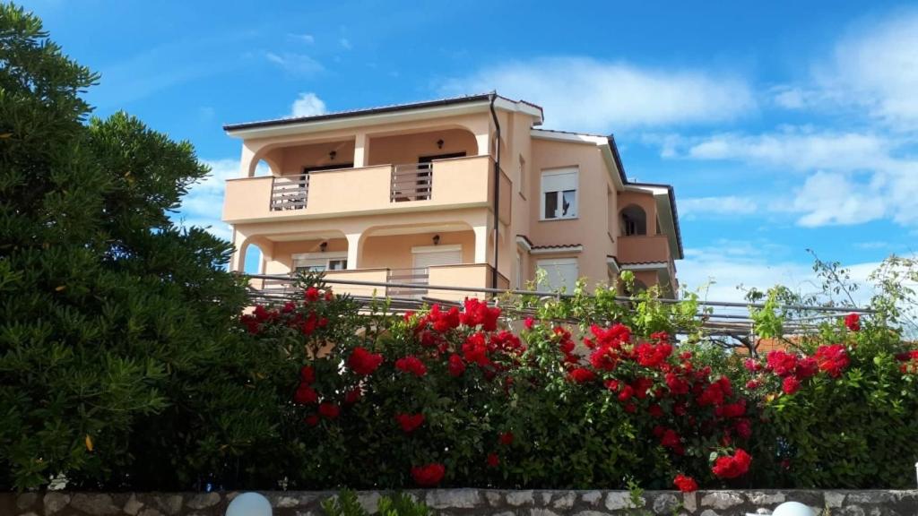 un bâtiment avec des fleurs rouges devant lui dans l'établissement Apartment in Lopar with Balcony, Air condition, WIFI (4224-2), à Lopar