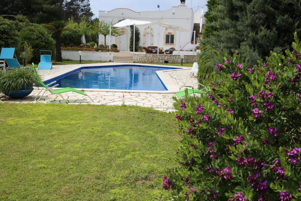 una piscina en un patio con flores púrpuras en B&B Le Vele, en Maruggio