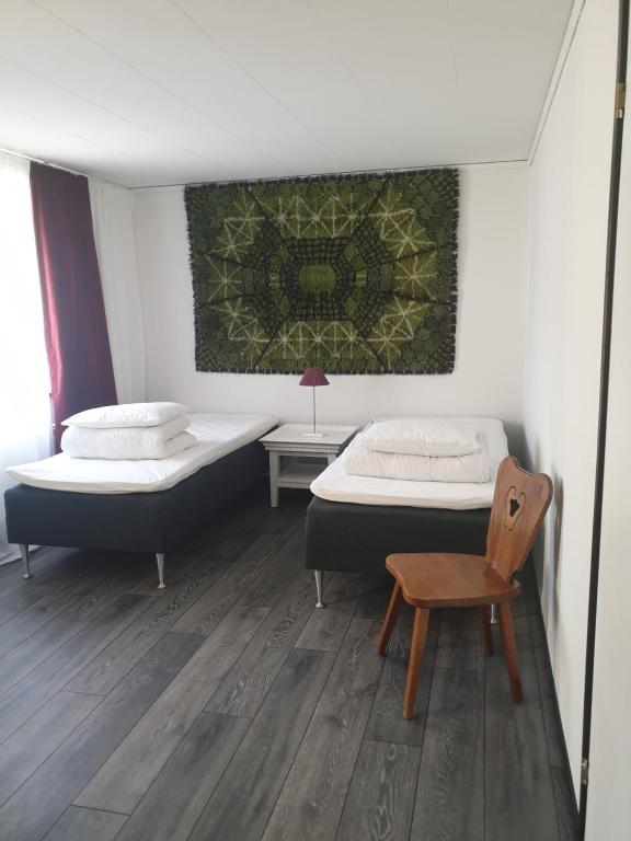duas camas num quarto com uma cadeira e um quadro em Rum på Österlen em Sankt Olof