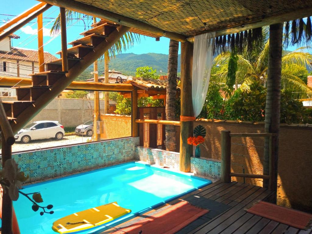 una piscina en una casa con terraza en Chalé de Charme MANDOMAI - Suítes com Cooktop e Chalé Charmoso com Cozinha, en Ilhabela