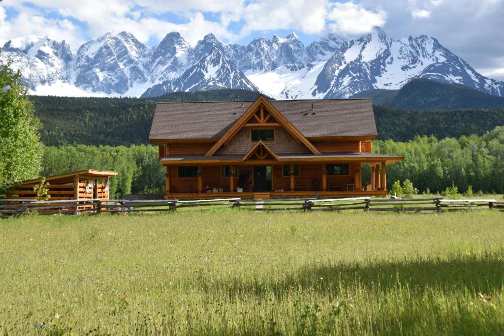a log cabin in a field with mountains in the background at Seven Sisters Mountains House in Kitwanga