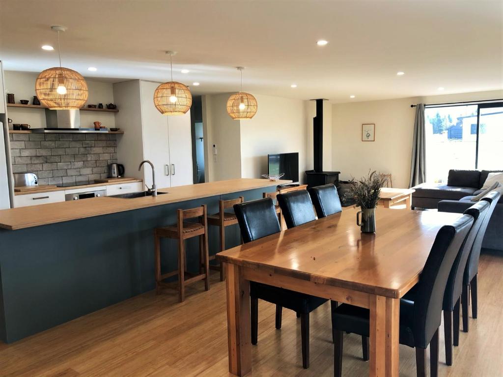 a kitchen and living room with a wooden table and chairs at Holiday Comfort in Twizel