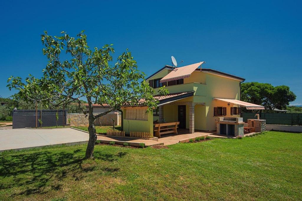 uma pequena casa com uma árvore no quintal em Holiday Home Sandi em Pula