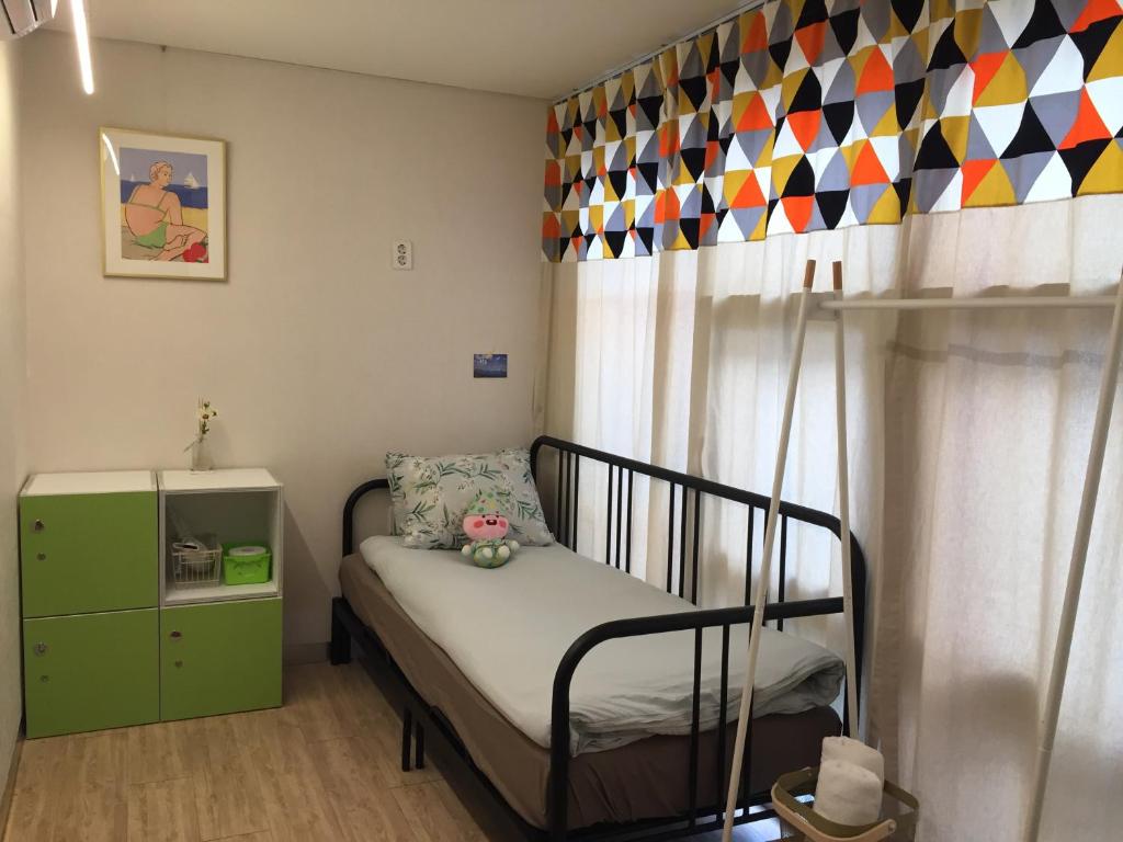 釜山にあるインサイド プサン ホステルの小さなベッドルーム(ベッド1台、緑のキャビネット付)