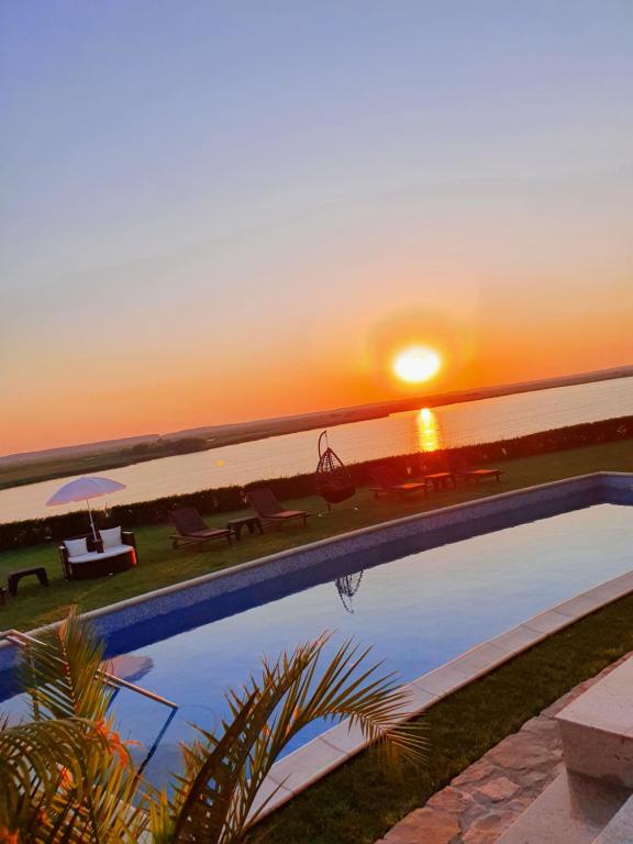 a swimming pool with a sunset in the background at Casa Miralago Boutique in Tulcea