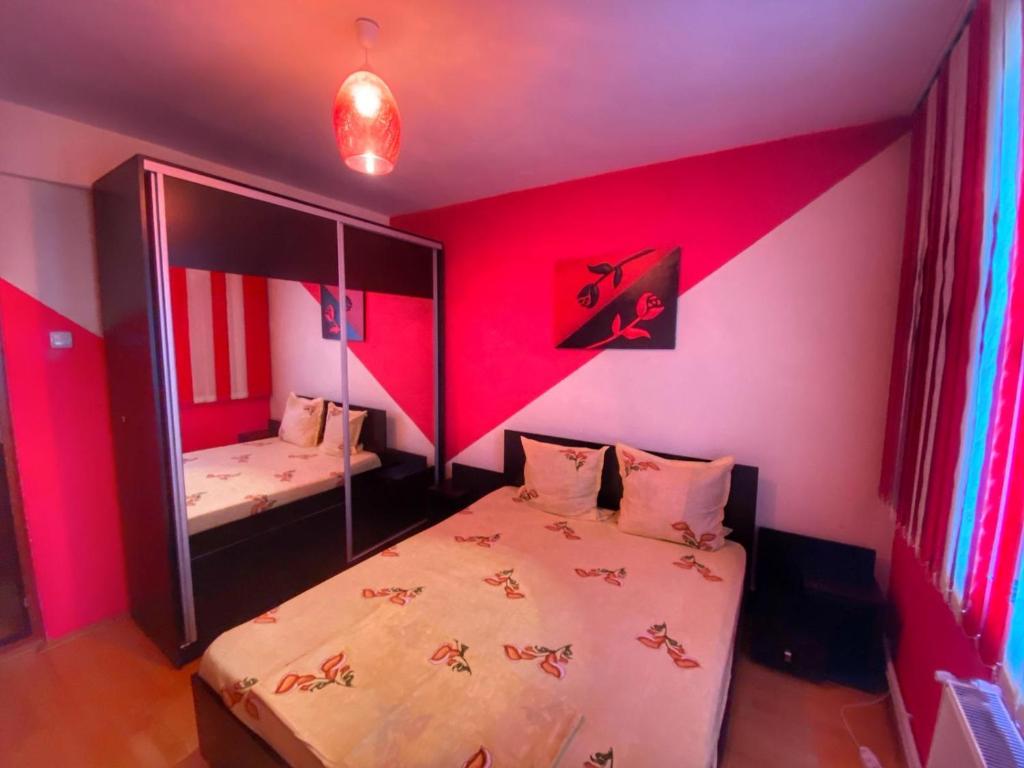 a room with a bed with pink walls and a mirror at Apartament Sira in Sulina