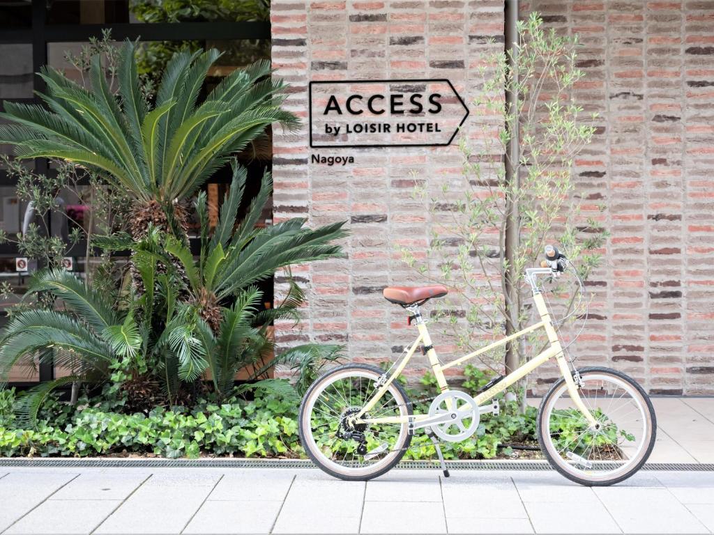 ein weißes Fahrrad, das neben einem Backsteingebäude parkt in der Unterkunft ACCESS by LOISIR HOTEL Nagoya in Nagoya