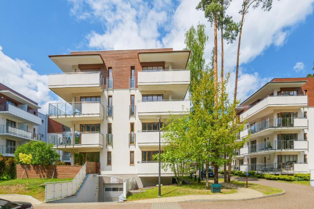 Contemporary four-story apartment building with balconies, landscaped grounds and tall trees