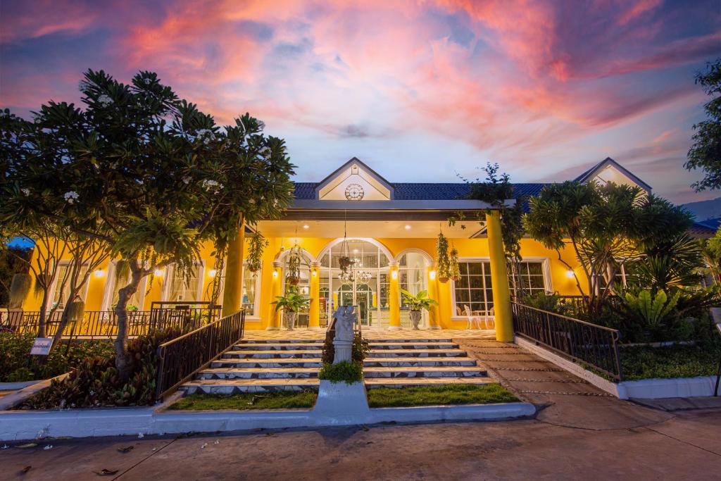 a yellow house with a staircase in front of it at Seattle Samaesarn Resort in Ban Samae San