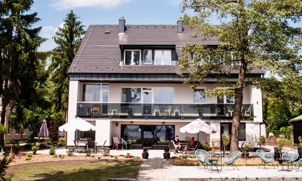 uma grande casa branca com mesas e cadeiras em frente em Q-Panzió em Tata