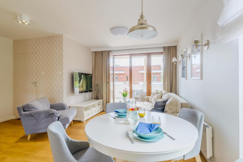 a living room with a white table and chairs at Apartamenty PIAMOLA Baltic Park Stegna in Stegna