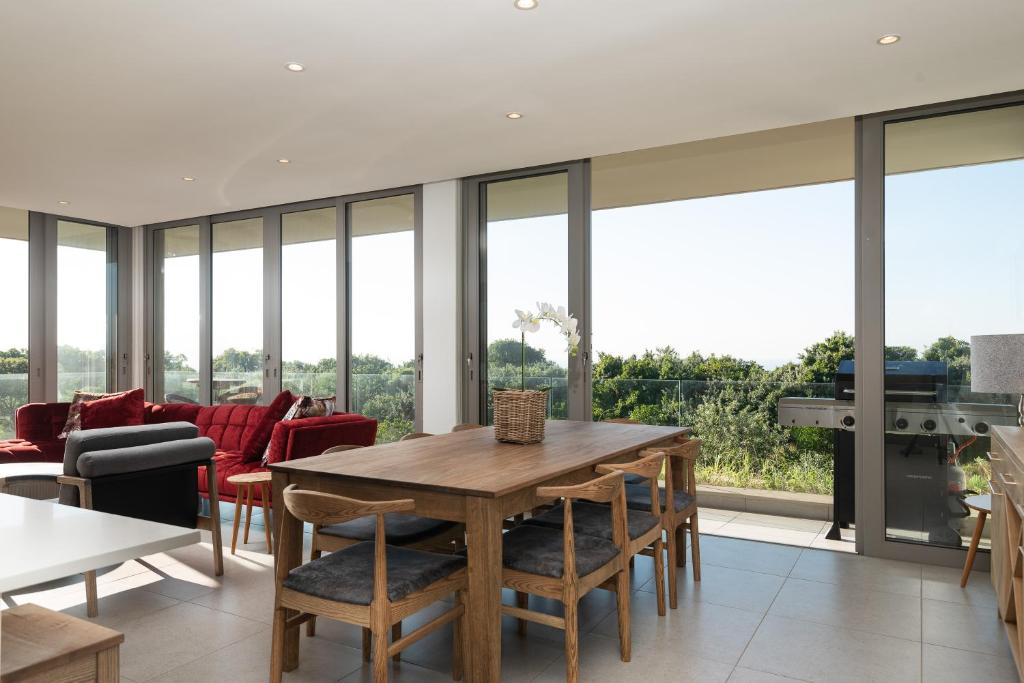 a dining room with a table and chairs and glass windows at 254 Ocean Dune Sibaya in Umhlanga