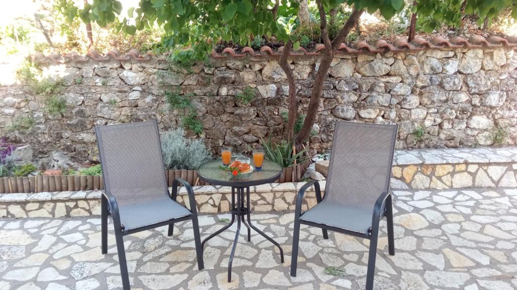 two chairs and a table in front of a stone wall at Sivotahomes-blu in Syvota