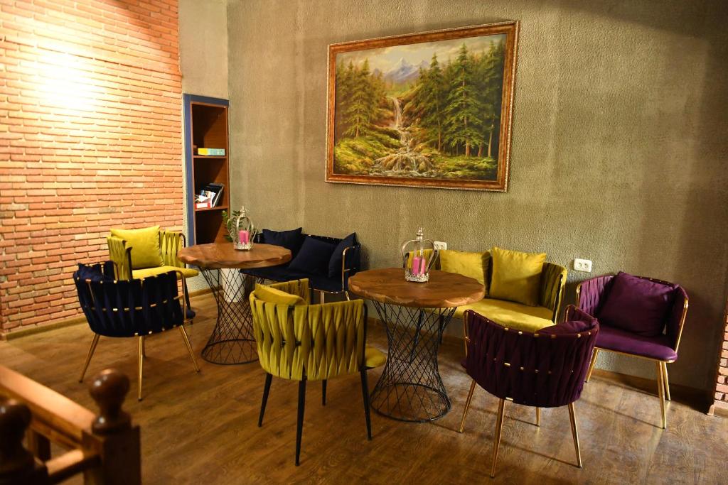 a restaurant with tables and chairs and a painting on the wall at CapsulePlus in Tbilisi City
