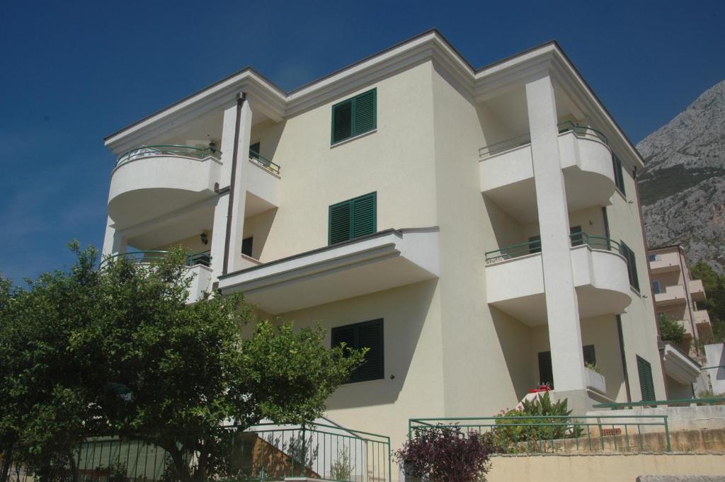 een wit appartementencomplex met een berg op de achtergrond bij Apartments Katarina 2 in Makarska