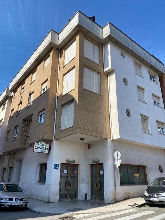a large building with two cars parked in front of it at Hotel Camagüey in Gijón