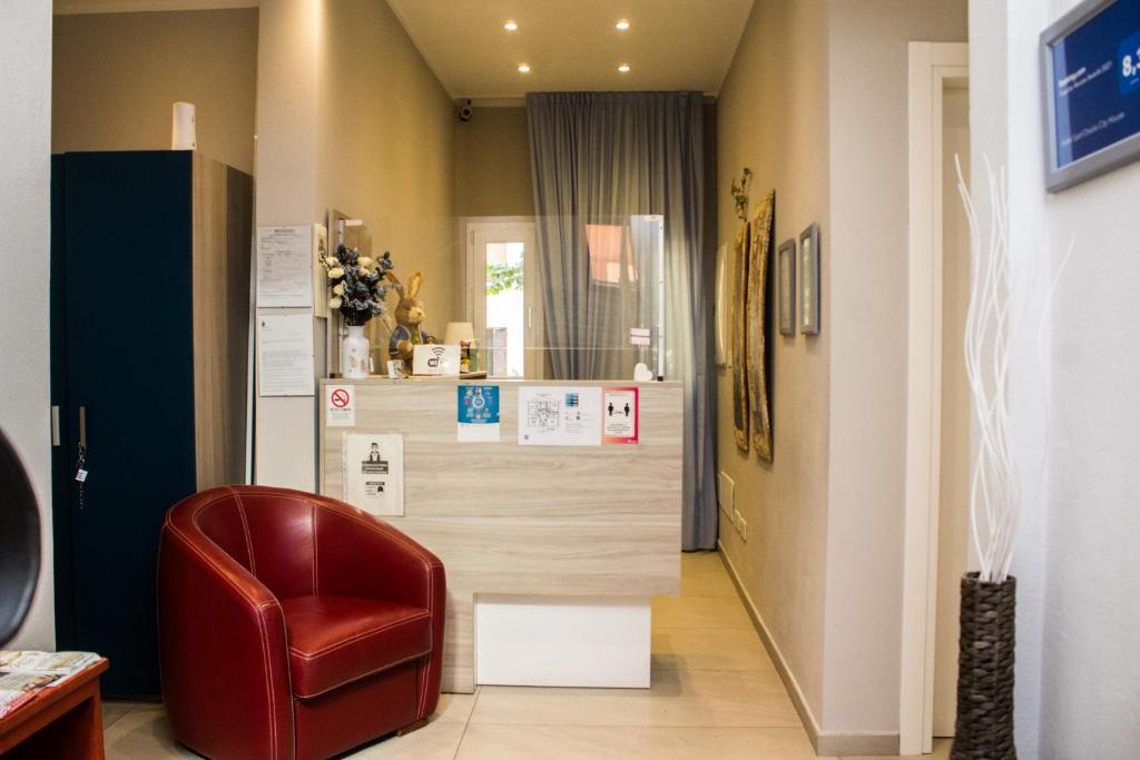 - un salon avec une chaise rouge et un comptoir dans l'établissement Hotel Sant'Orsola City House, à Bologne