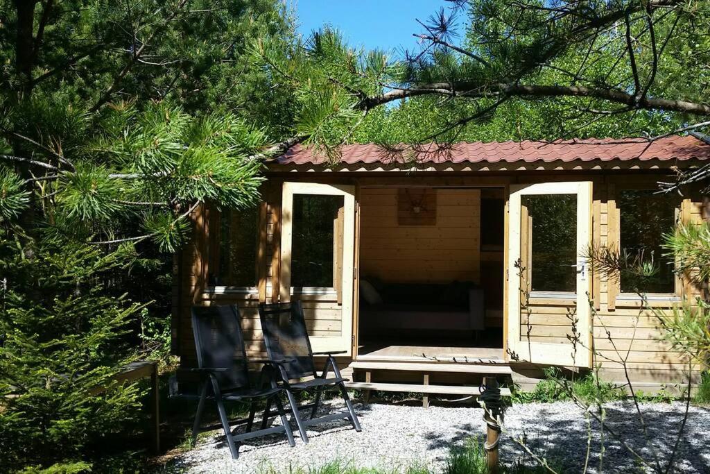 a small cabin with two chairs in front of it at Cozy Lodge in Värmland Sweden in Filipstad