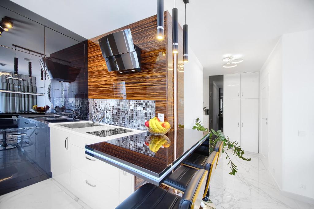 uma cozinha com armários brancos e um balcão preto em Apartament Clipper em Mielno