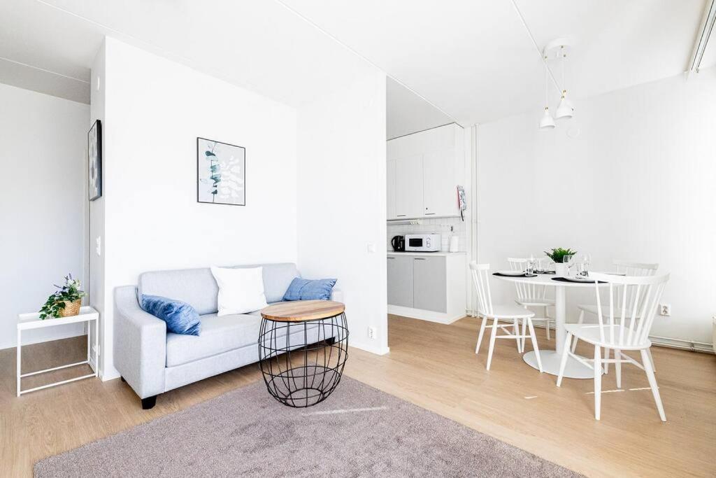 a white living room with a couch and a table at Apartment Sleepwell, Leppävaara, 71m2 with private sauna in Espoo