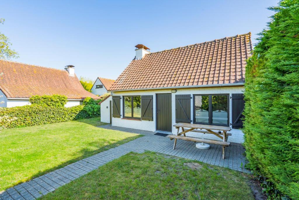 a house with a picnic table in the yard at Cottage 213 in Sunparks Oostduinkerke with free parking and garden in Koksijde