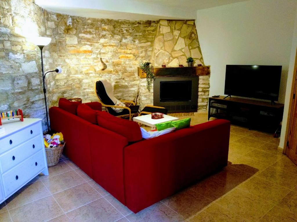 a living room with a red couch and a fireplace at Casas Los Carabos El Refugio in Letur