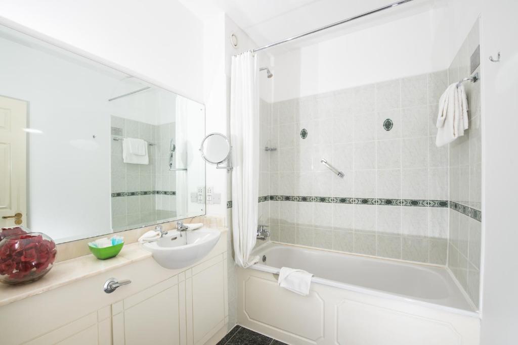 un bagno bianco con lavandino, vasca e lavandino di Killarney Lodge a Killarney