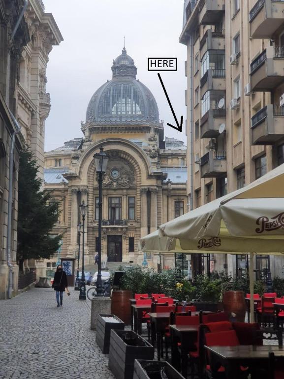 a building with a clock tower and tables and chairs at Bucharest Pedestrian Old Town 3 Bedrooms by Orchid Garden in Bucharest